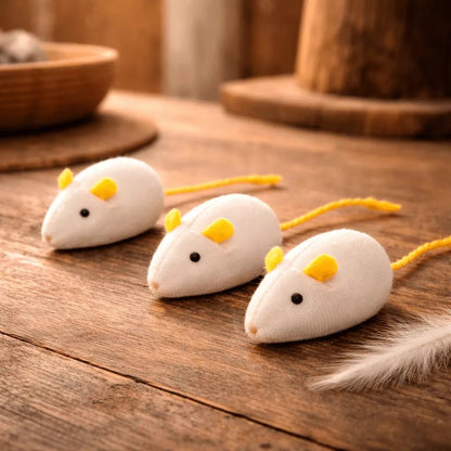 Jouet souris pour chat en pack de 3 blanc avec oreilles et queue jaunes posé sur surface en bois