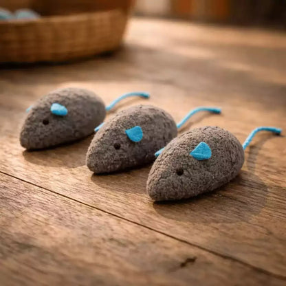 Jouet souris pour chat en pack de 3 gris foncé avec oreilles et queue bleues posé sur plancher en bois