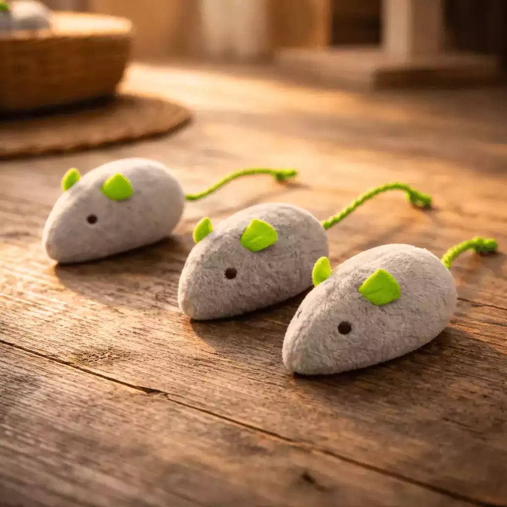 Jouet souris pour chat en pack de 3 gris avec oreilles et queue vertes posé sur surface en bois